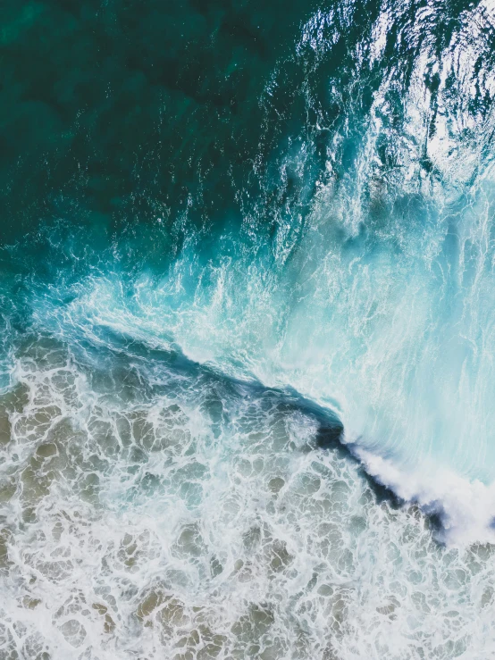 a top down s of a wave crashing into shore