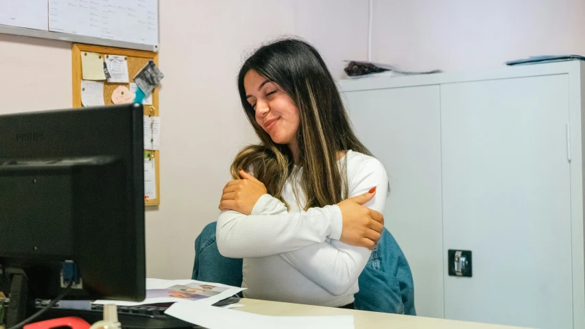 a woman hugs her child sitting at a computer