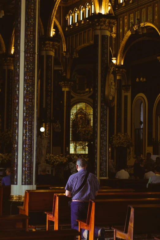 man sitting in church alone on chairs facing towards alter