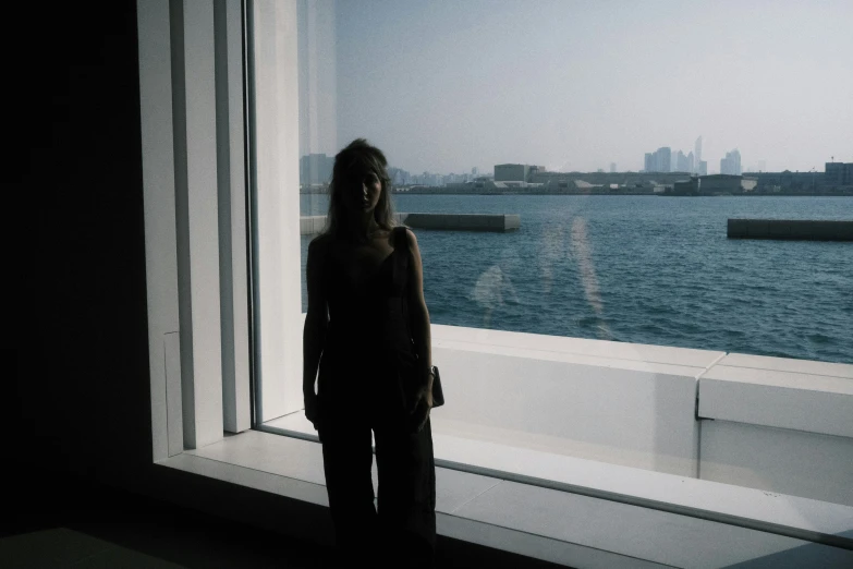 a woman standing next to a window overlooking water