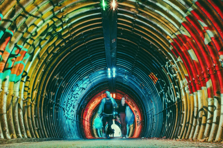 several people walking in a tunnel with a lot of graffiti on the walls