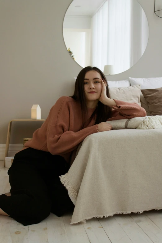 a young woman sitting on a bed smiling for the camera