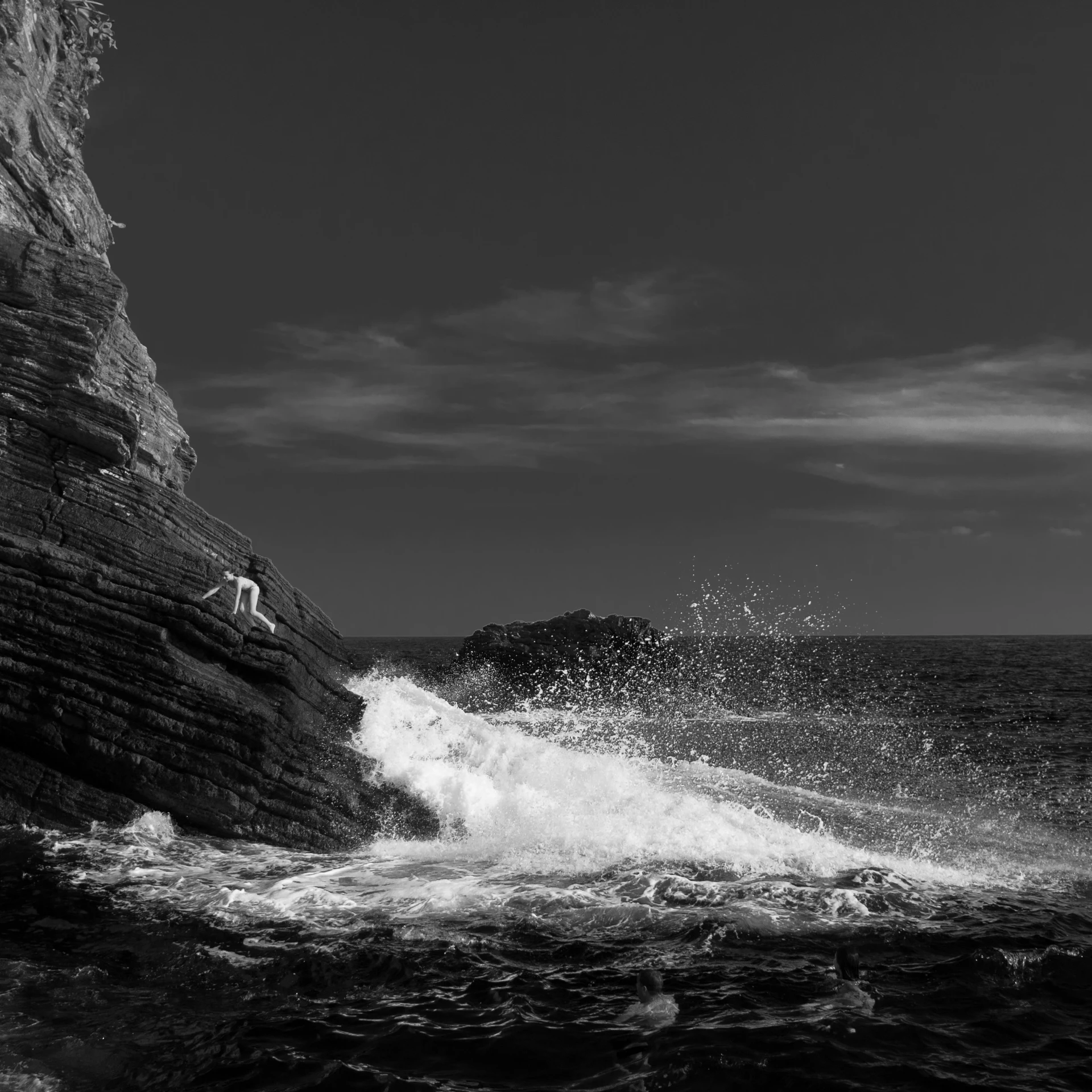 black and white pograph of a person jumping off a rock into water