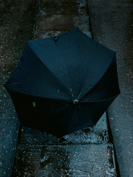 an open umbrella sitting on the pavement during a rainy day