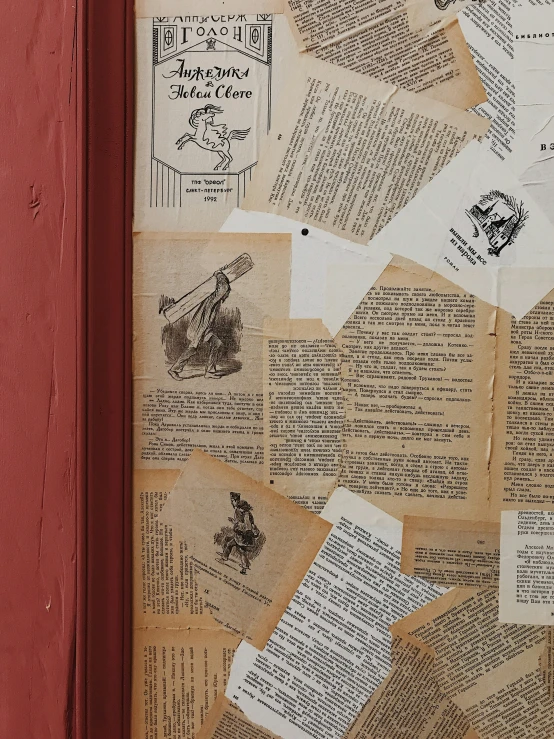 old papers and some type on paper attached to a red wall