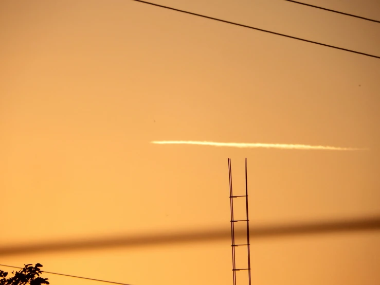 there are two power lines with the sun low in the background