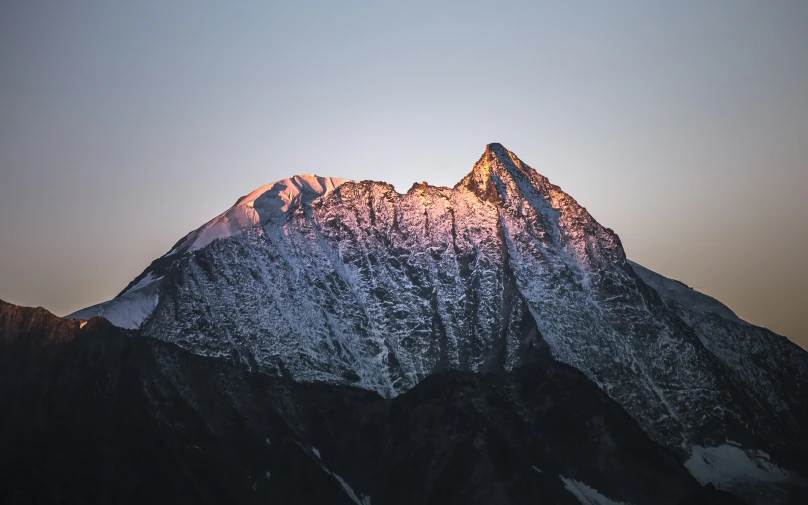 a large snow covered mountain with a plane flying high above it