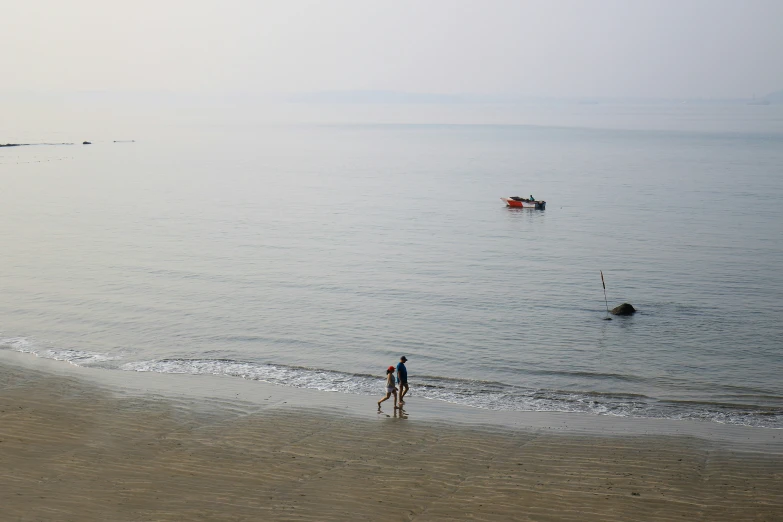 people are at the beach by some boats in the water