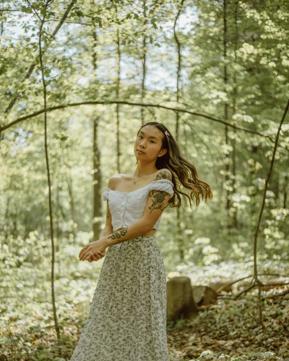 a young woman is wearing a long skirt in the woods