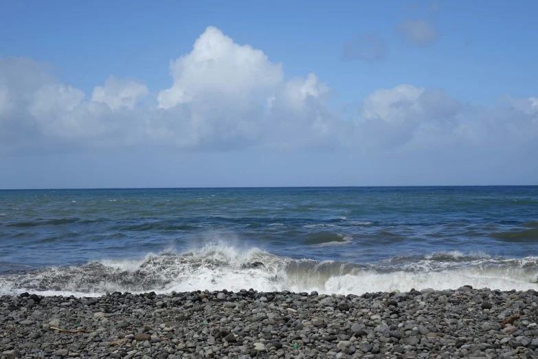 a rocky beach with a surfboard stuck in the gravel