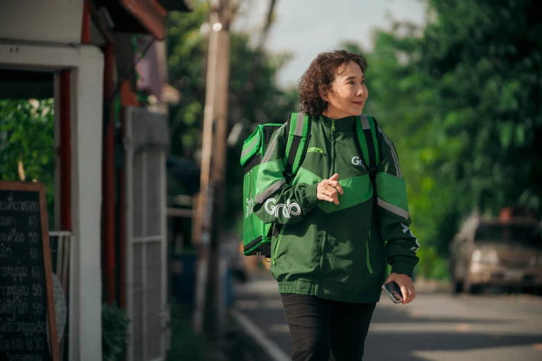 the woman is wearing a green coat and holding a cellphone