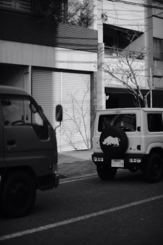 two cars are driving on the street beside building