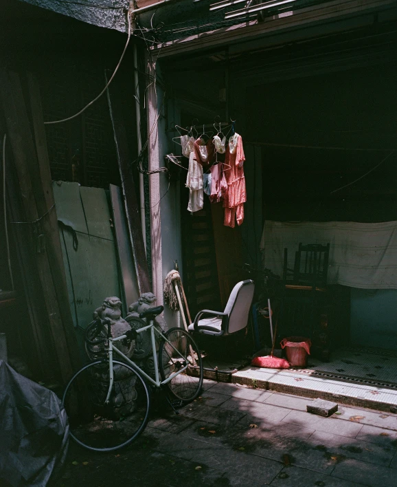 a room with an old chair, bike, and clothes