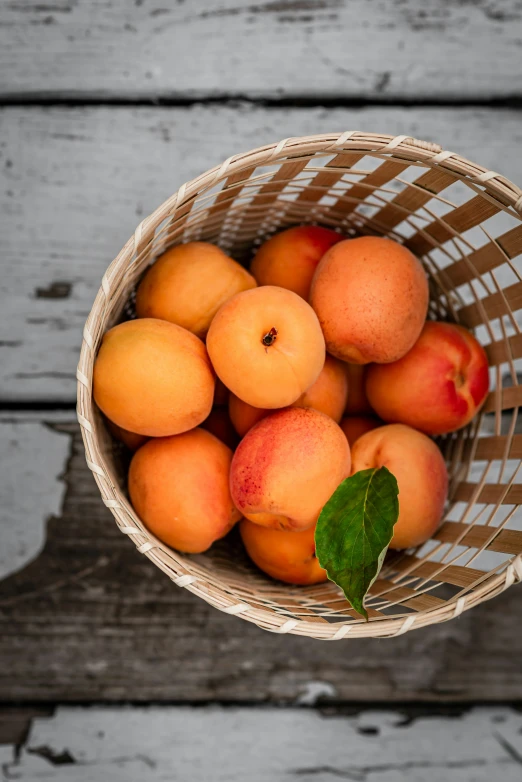 a basket with peaches inside sits on a table