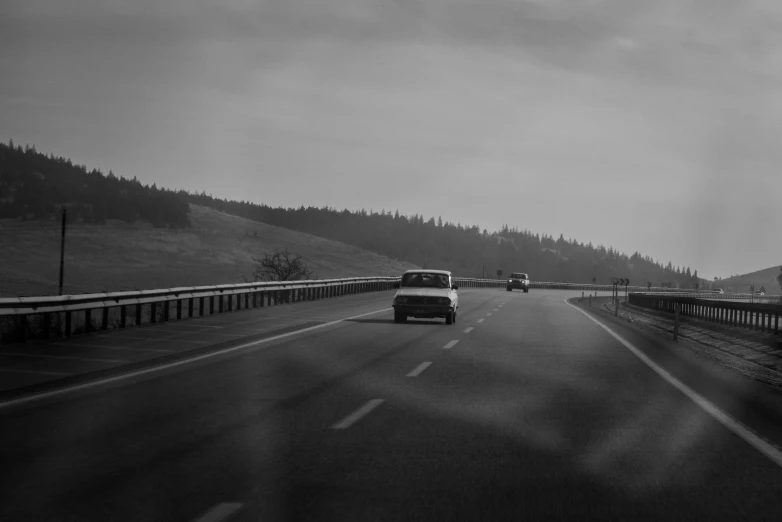 a highway with two cars on it and trees