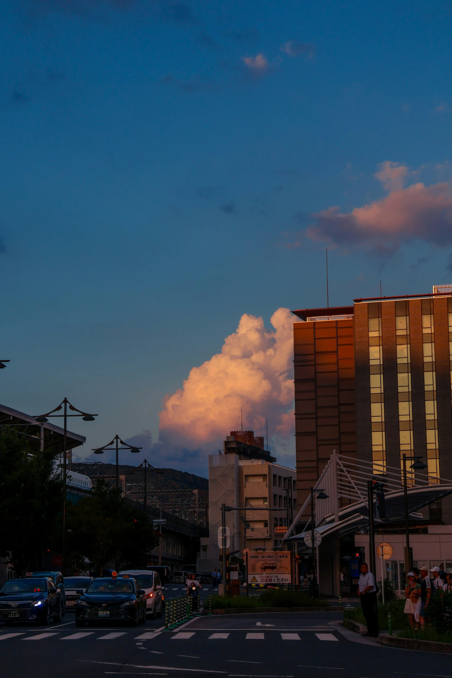 a few clouds over buildings and some cars