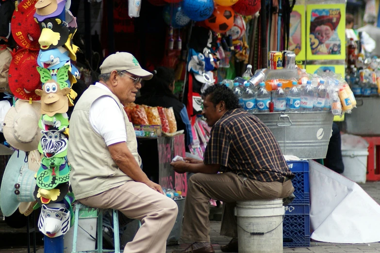 two men sitting outside of a colorful store