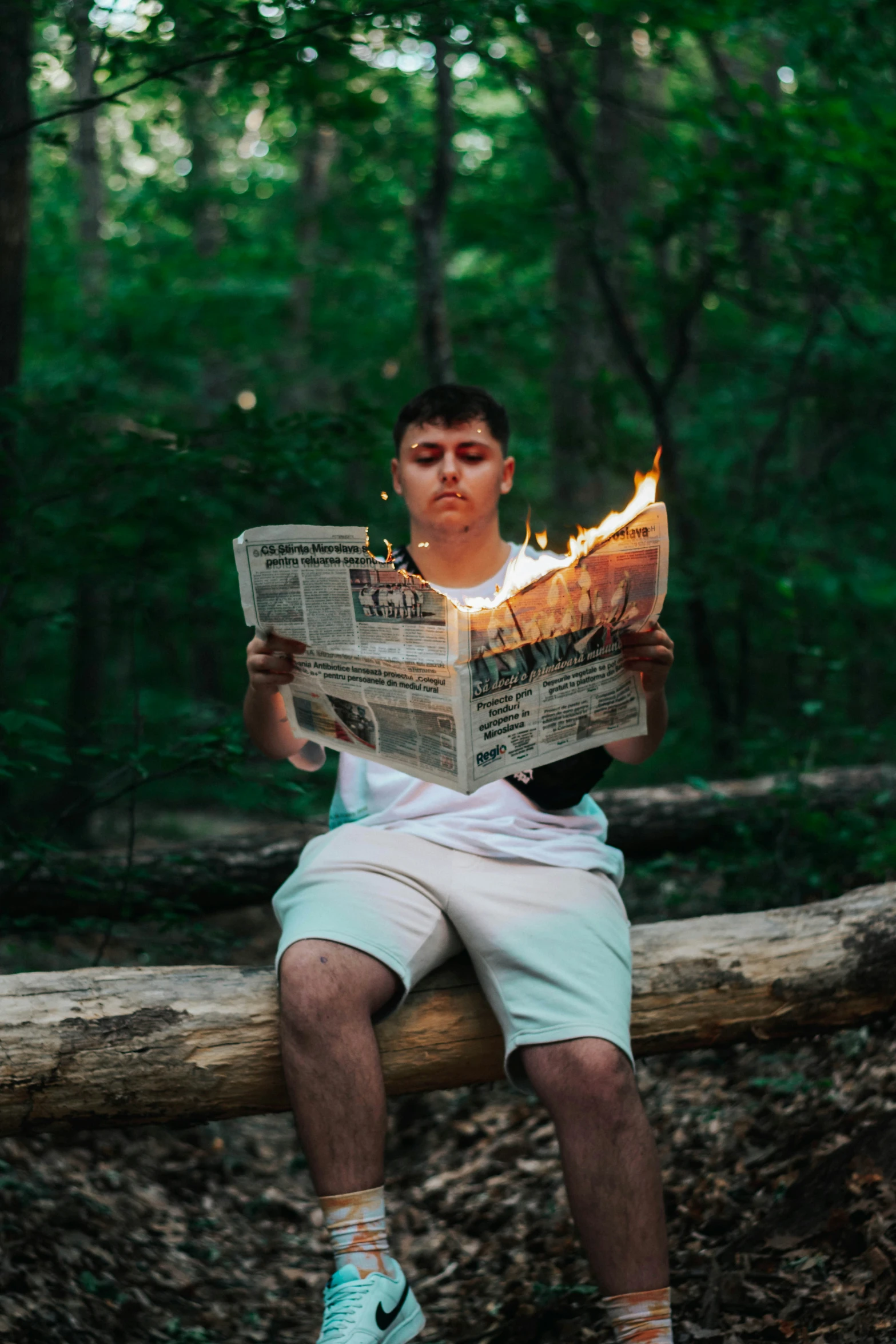 a man is sitting on a log reading the paper