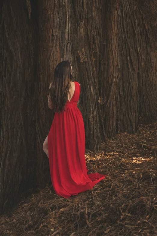 a little girl standing by the tree in red