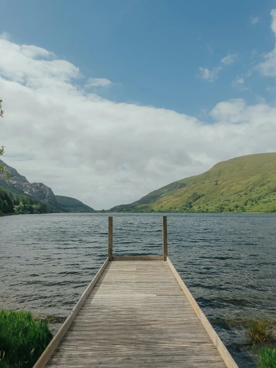 an empty dock on a lake next to mountains