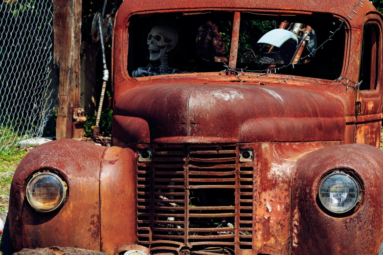 a worn, rusty truck is sitting by a fence