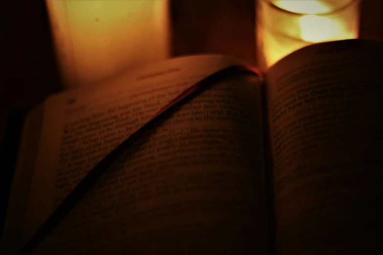 an open book, sitting in front of a lit candle