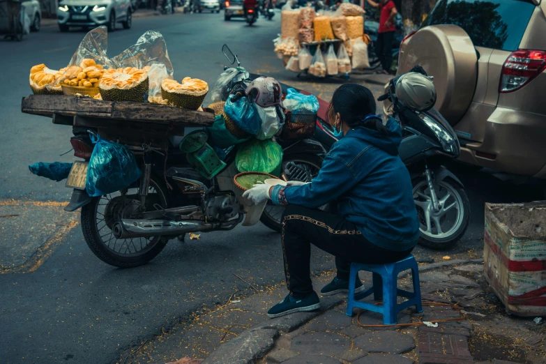 a man sitting on a stool next to his parked motorcycle