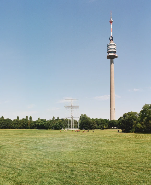 a tall tower stands behind a large field