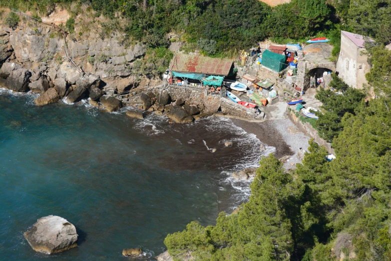 aerial view of a home on the ocean with a tent, canoe and swimming pool