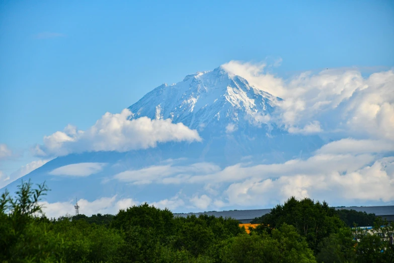 some clouds float in the air above a snow covered mountain