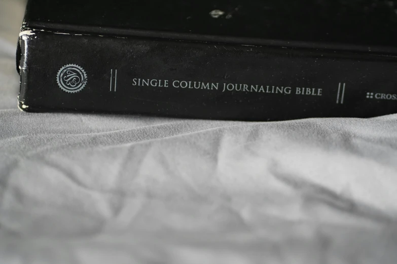 a black book with a white cover laying on a bed