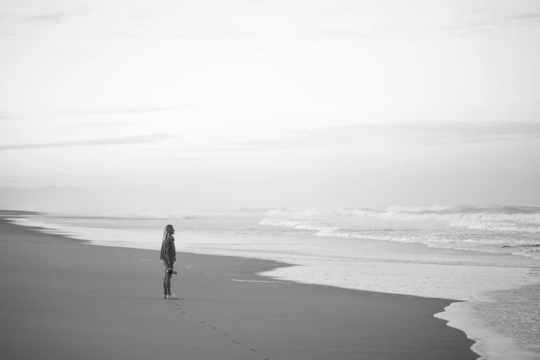 a black and white po of someone walking on a beach