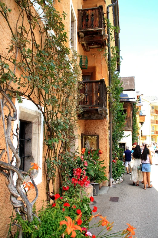 several people walking on the sidewalk in front of some buildings