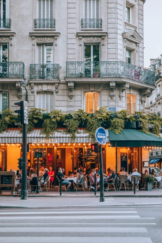 people are sitting at tables in front of some tall buildings