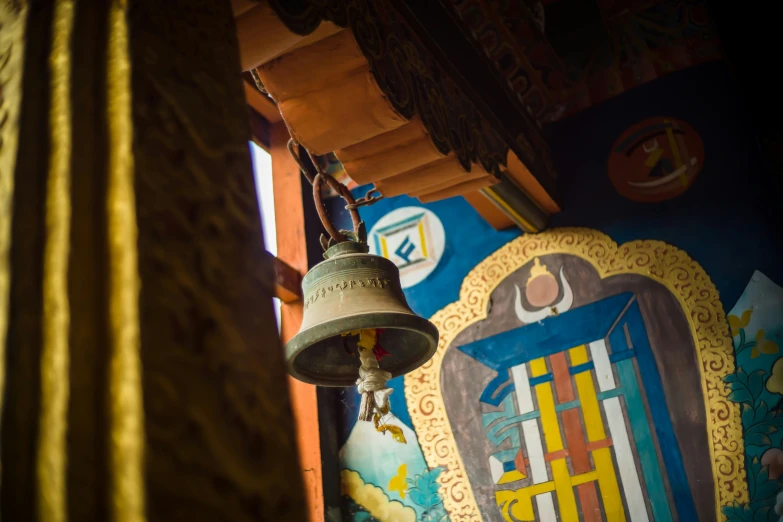 a bell hangs next to a painting hanging above