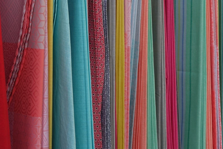 various colored fabric on racks next to each other