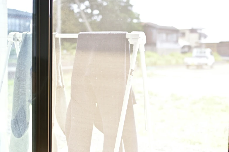 towels and blankets hang up in front of an open window