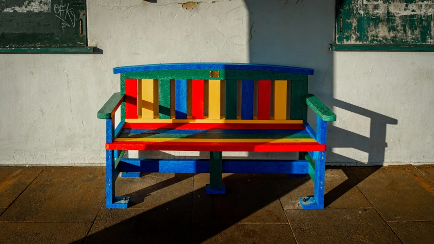colorfully painted wooden bench next to white stucco wall