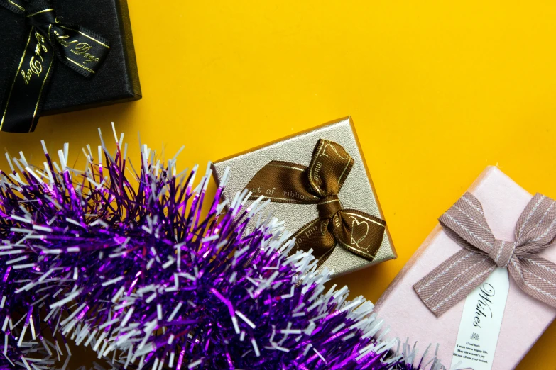 a wrapped christmas present and purple tinsel next to a tree