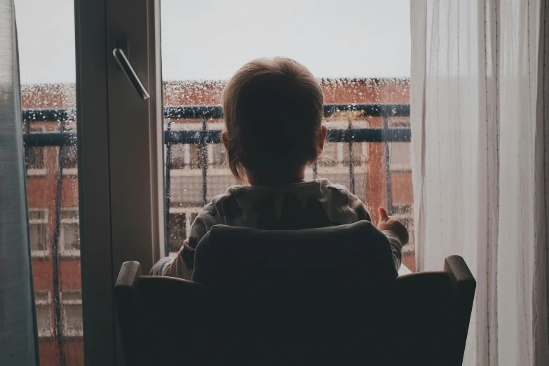 a child looking out of a window during a rainy day