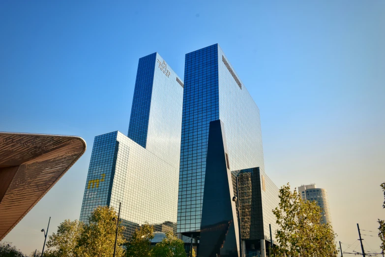 two tall buildings near each other in front of some trees