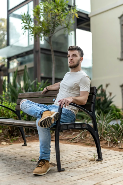 a young man is sitting on a bench outside