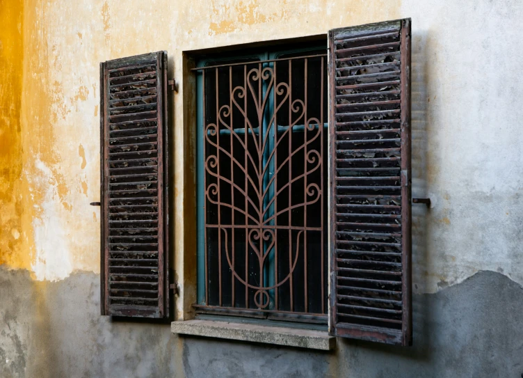 an old window with a iron screen and barred shutters