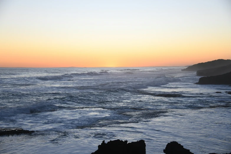 the sun is setting over the water off the shore