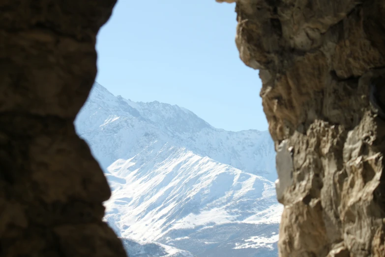 a rock wall and a white snow mountain