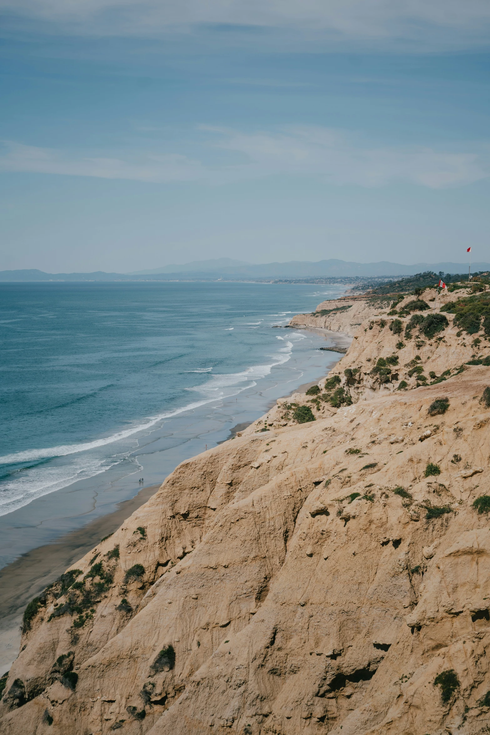 a beach with a hill side next to the ocean