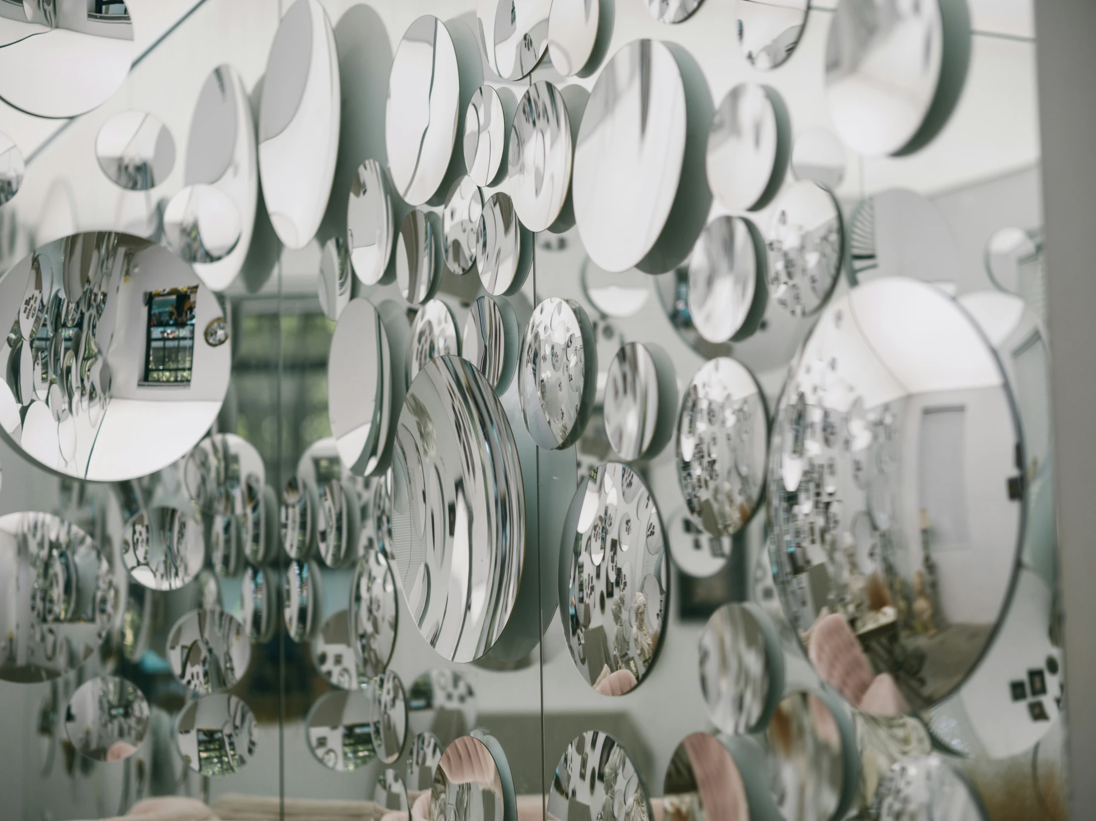 a mirror displays many different clocks hanging from it