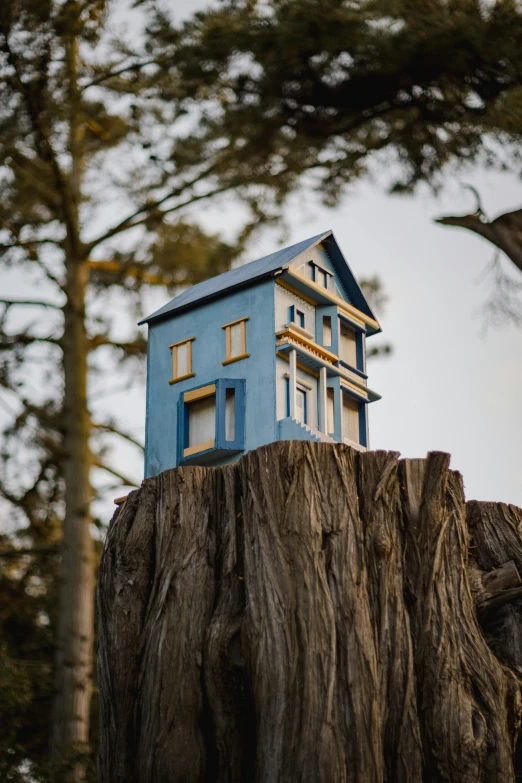 a toy house sits on top of a tree stump