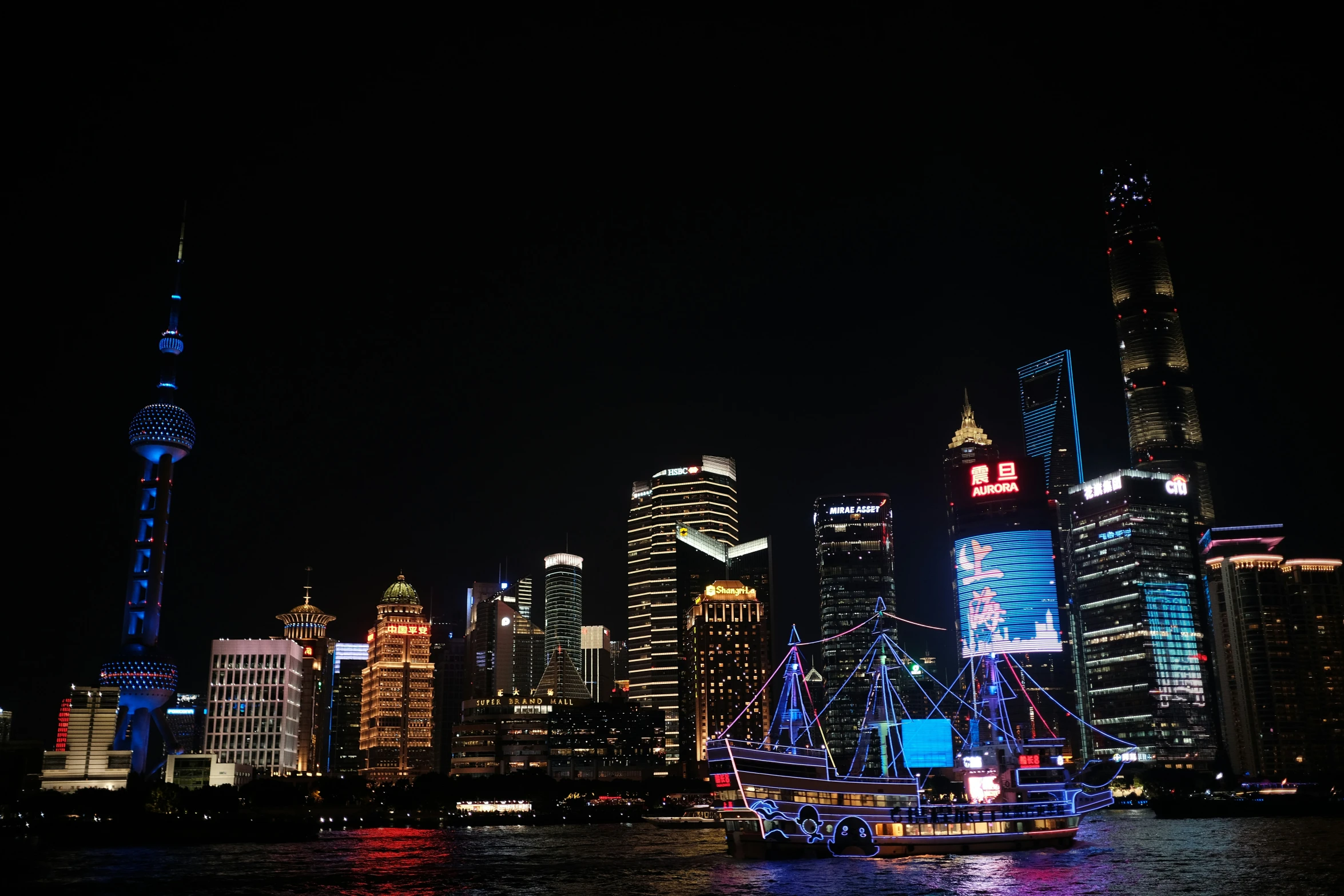 a boat travels down a large river in front of some illuminated buildings