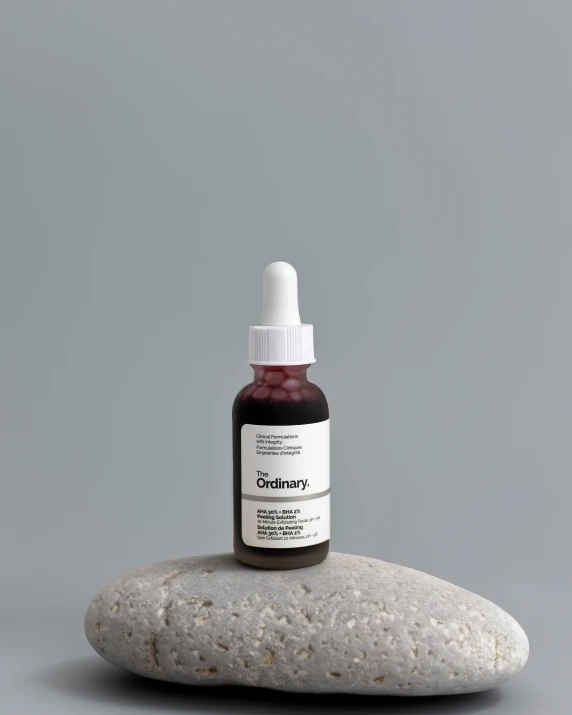 a glass bottle filled with liquid sitting on top of a white stone